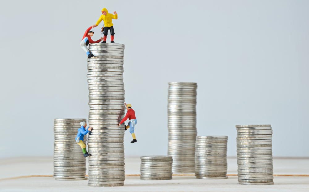 Miniature climbers team climbing on stack of coins